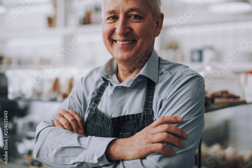 Joyful senior man standing with arms crossed over his chest