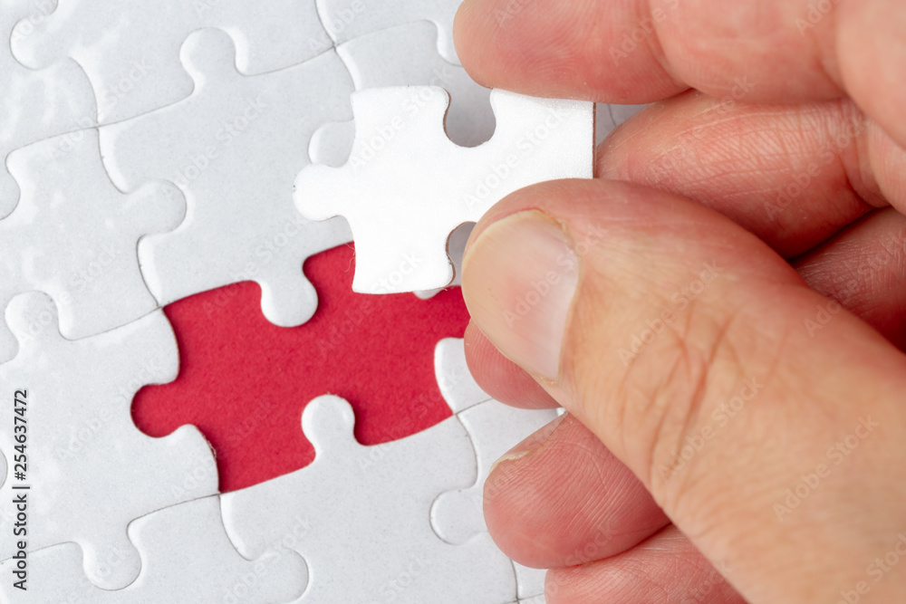 Hand put the last piece of jigsaw puzzle to complete the mission Hand put the last piece of jigsaw puzzle to complete the mission