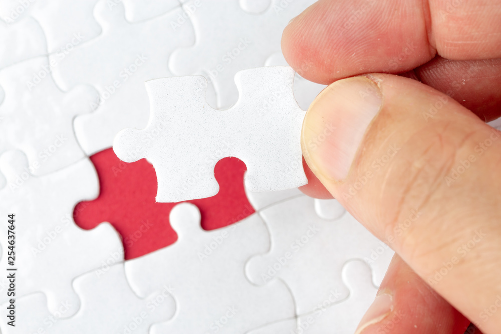 Hand put the last piece of jigsaw puzzle to complete the mission Hand put the last piece of jigsaw puzzle to complete the mission