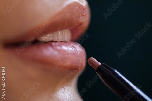 Close up of beautiful makeup on wet female lips against dark background