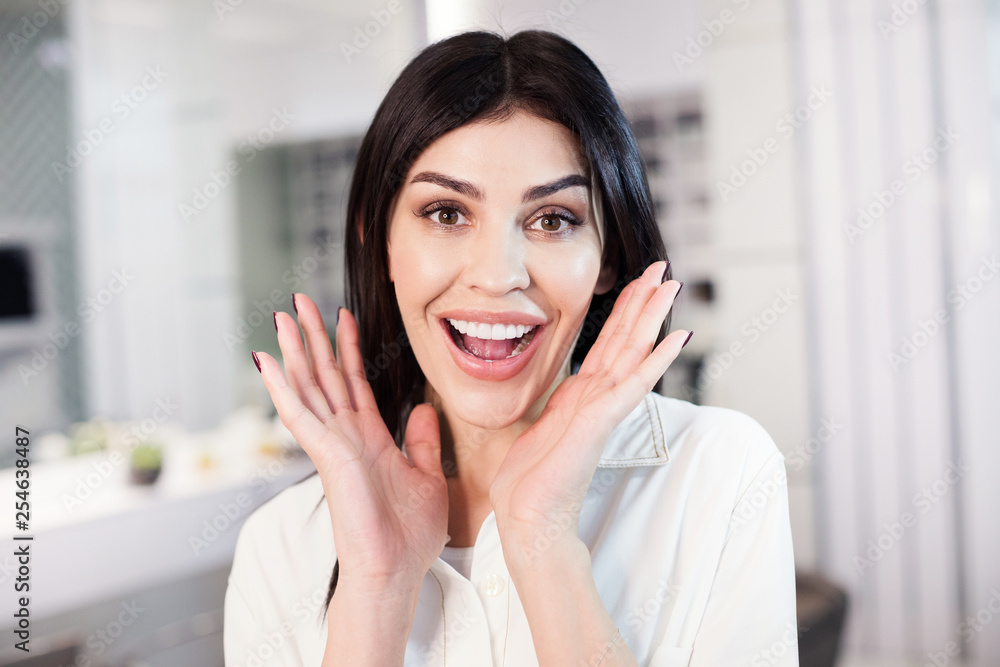 Portrait of excited woman with beautiful makeup situating in barber shop