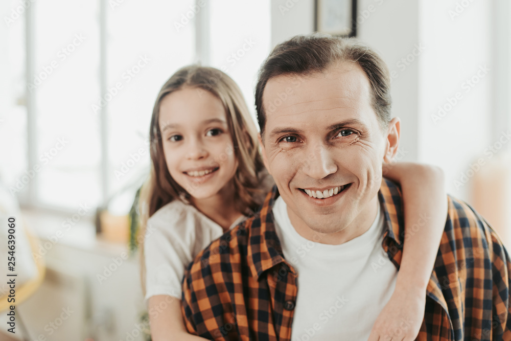 Close up of smiling man and daughter hugging him Close up of smiling man and daughter hugging him