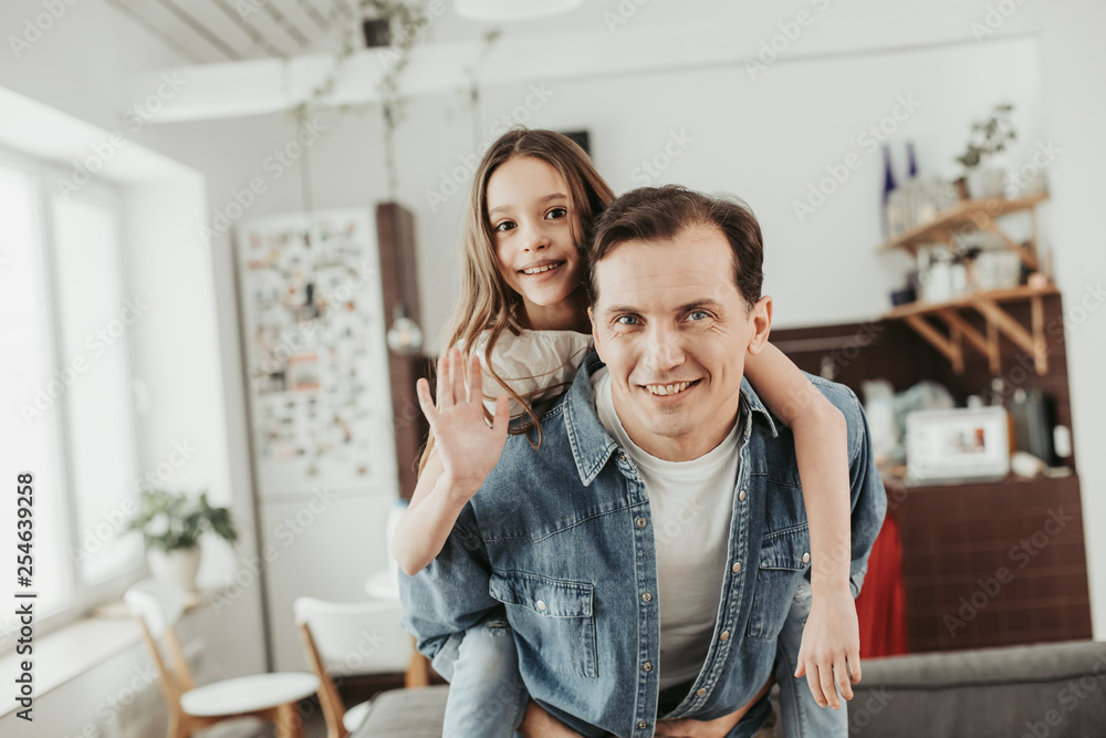 Cute girl sitting on the back of her father and waving her hand Cute girl sitting on the back of her father and waving her hand