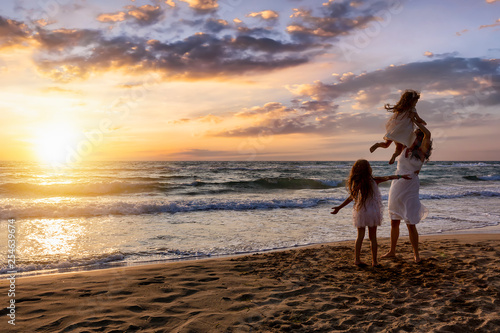 Mutter im Familienurlaub mit ihren Töchtern hat Spaß am Strand bei Sonnenutergang