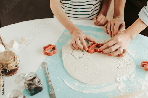 Hands of two people putting heart shaped cookie cutter on the dough