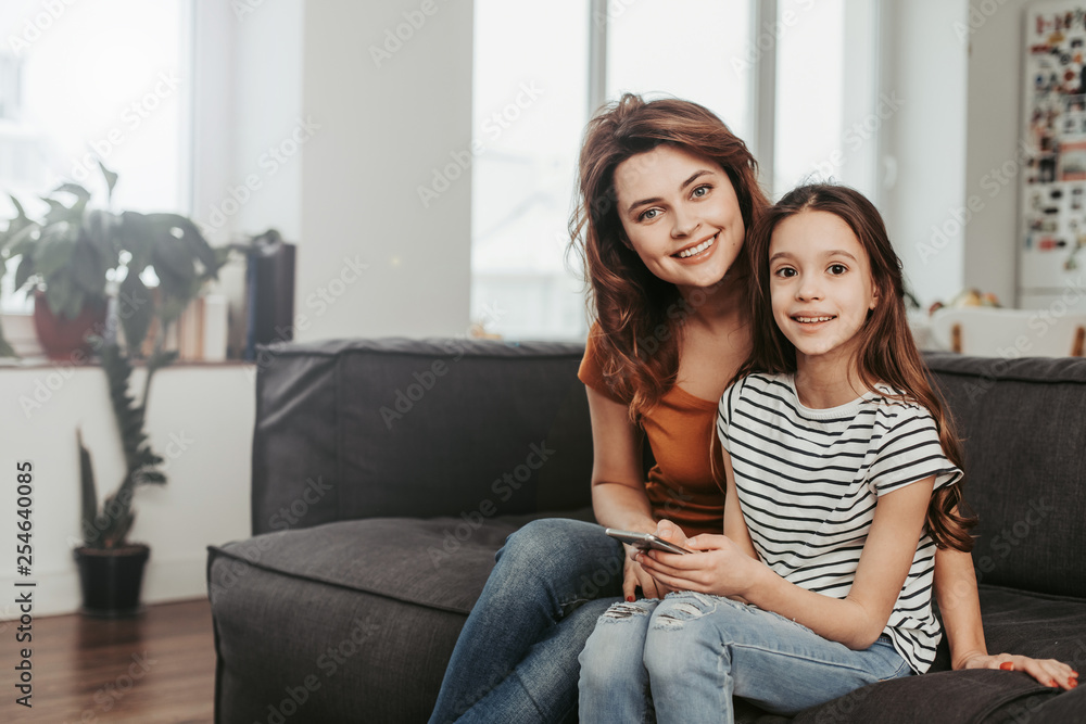 Mother and daughter sitting on sofa at home