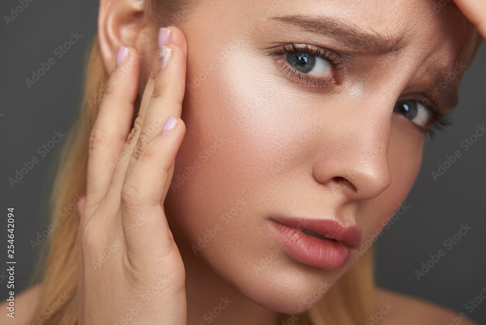 Worried woman frowning and checking her skin on the face Worried woman frowning and checking her skin on the face