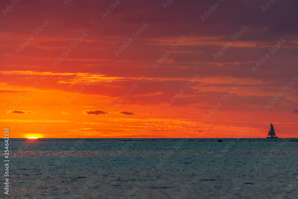 Sailing vessel sails on the burning sunset background on the calm surface of vastless Indian ocean Sailing vessel sails on the burning sunset background on the calm surface of vastless Indian ocean