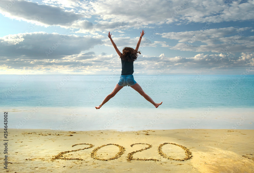 New Year 2020 on the sand,happy girl with hands up jumping on the beach