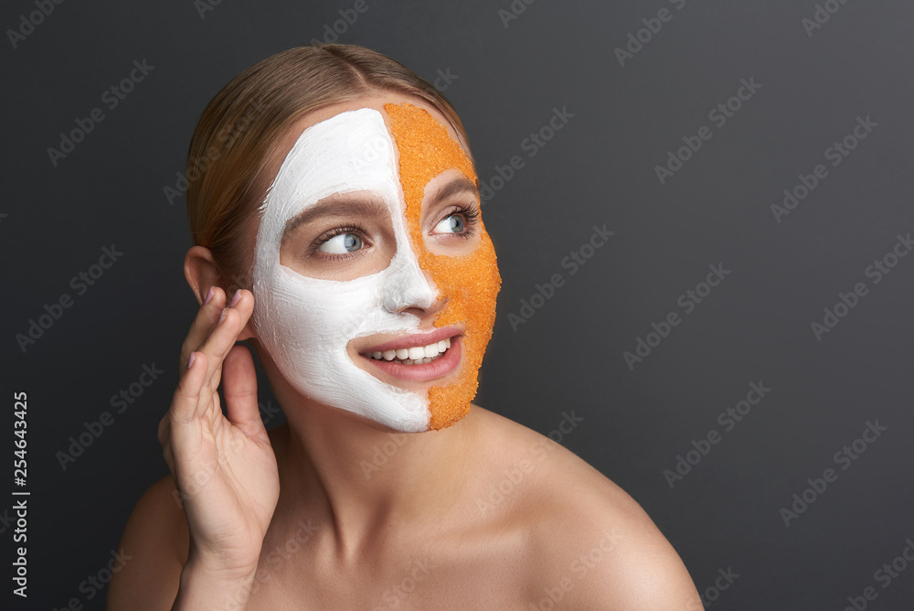 Happy woman smiling and touching her face with white and orange mask