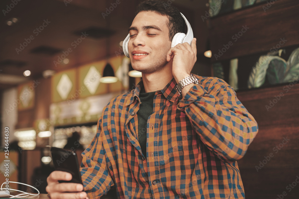 Handsome afro american guy using wireless headphones for listening to music Handsome afro american guy using wireless headphones for listening to music