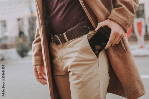 Young man getting smartphone out of his pocket photo