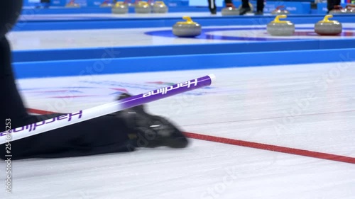 Curling player throw and delivering a stone on a curling rink, sliding over ice