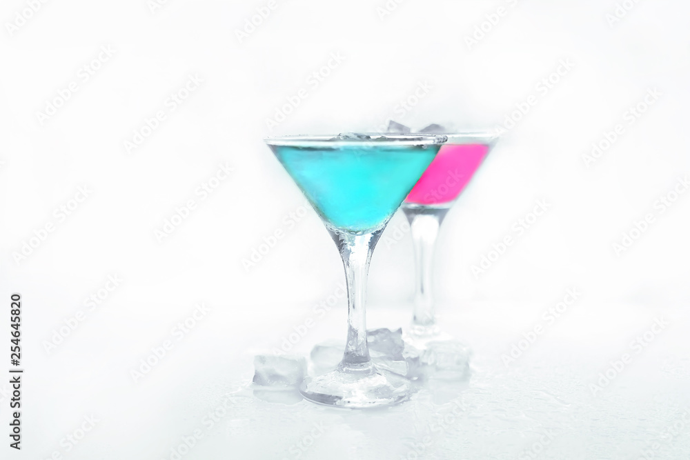 martini glasses with colored drinks and ice cubes.