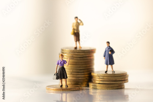 Concept of Retirement Money Plan and savings growth. Old and young woman stand on stacks of gold coins isolated on white and orange background.