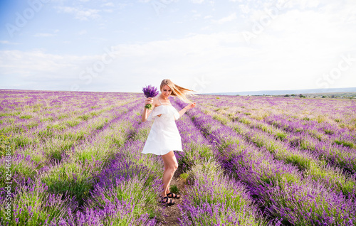 Girl in white dress in field of lavender with bouquet 