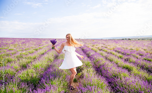 Girl in white dress in field of lavender with bouquet 