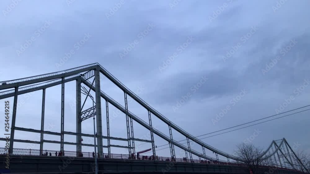 Pedestrian bridge over the river. Silhouette of the bridge on which people walk. Pedestrian bridge over the river. Silhouette of the bridge on which people walk.