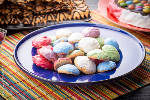 Piccoli biscottini rotondi glassati e colorati nel piatto di ceramica blu sul tavolo