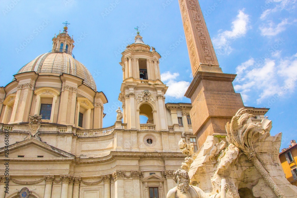 Fountain of the Four Rivers with an Egyptian obelisk and Sant Agnese Church on the famous Piazza Navona Square. Sunny summer day. Rome, Italy. Architecture and sights of Rome.