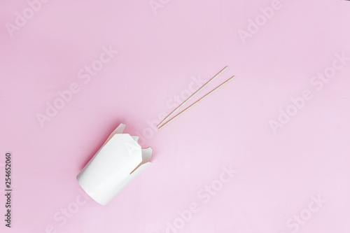 Opened takeaway box for chinese noodles presented with chopsticks, on pink background Retail set flatlay copyspace photo