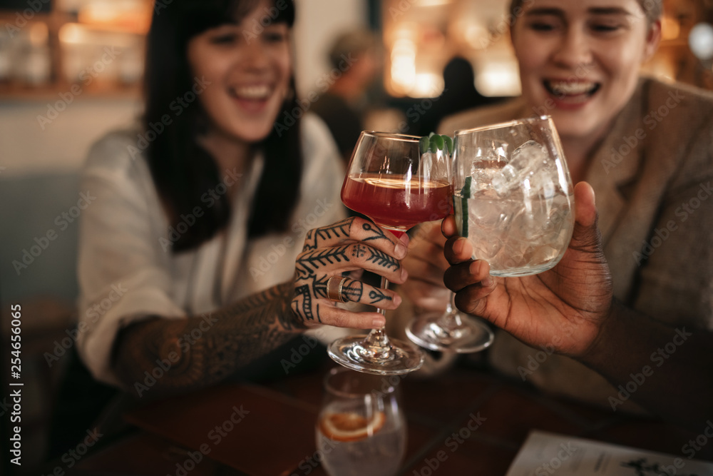 Smiling friends toasting together with drinks in a bar