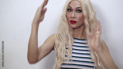 Funny comedic shot of a beautiful transgender woman making a huge gesture with her hands indoors 