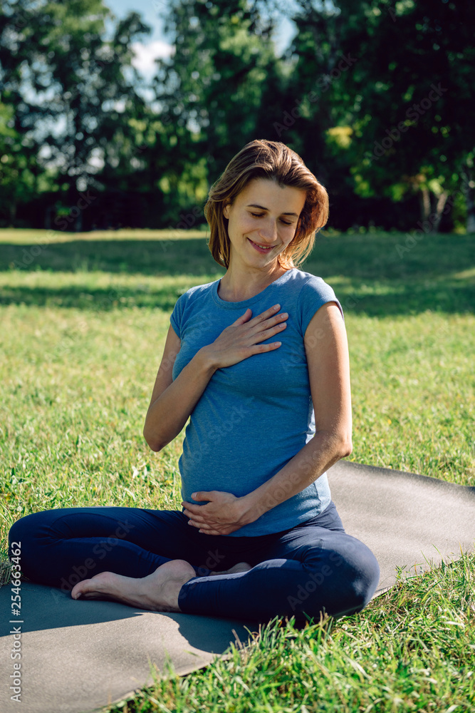 Young pregnant woman practicing yoga and meditation in the park Young pregnant woman practicing yoga and meditation in the park