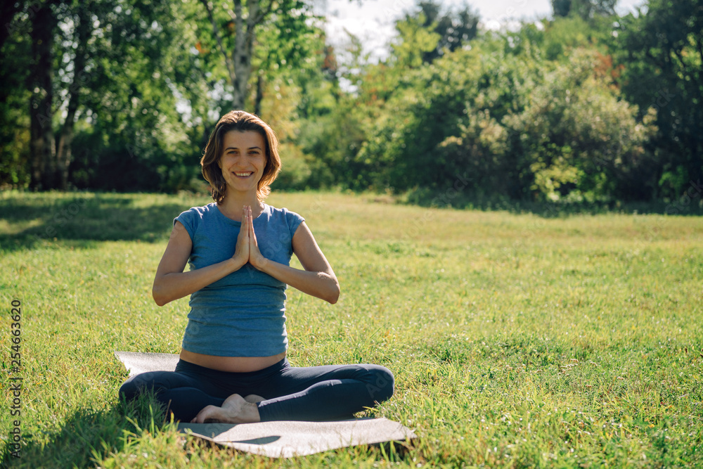 Young pregnant woman practicing yoga and meditation in the park Young pregnant woman practicing yoga and meditation in the park