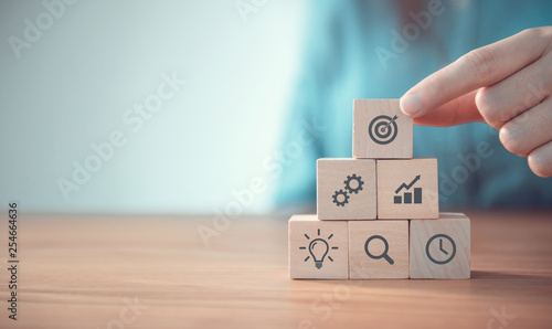 Businesswoman hand arranging wood block with icon business strategy and Action plan, copy space.