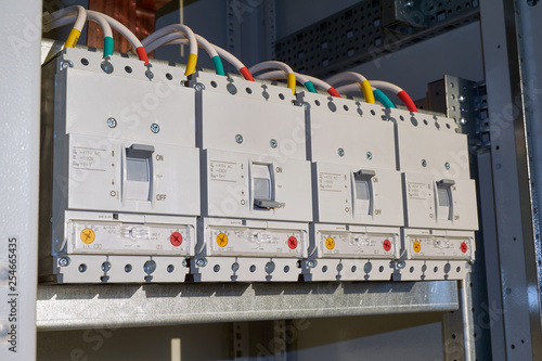 Four powerful industrial circuit breakers are fixed in the electrical Cabinet in line. Modern and reliable switches for power distribution in buildings. Technologies of production and connection of wi