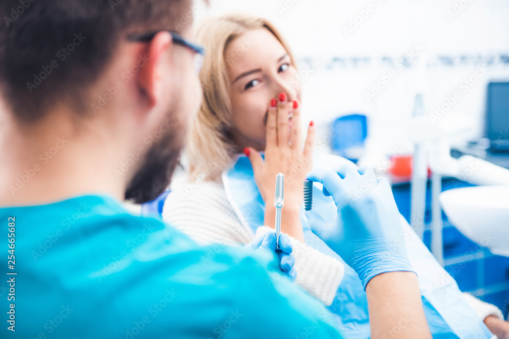 Dentist showing gray implant model to patient Dentist showing gray implant model to patient