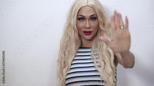 Close-up shot of a beautiful transgender woman doing the stop hand gesture with her arm outstretched to camera