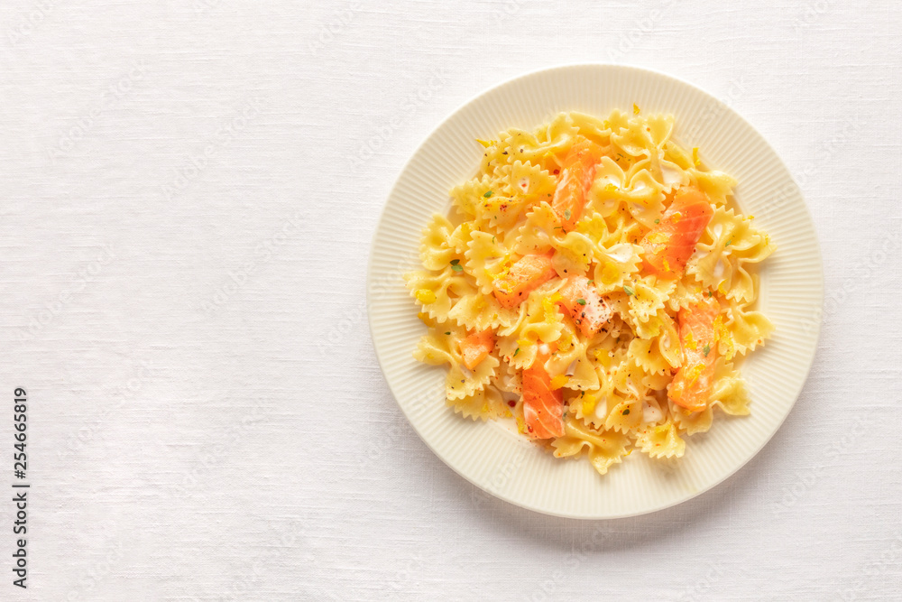 Smoked salmon with farfalle. Pasta with salmon and a cream sauce, shot from the top on a white linen table cloth with a place for text Smoked salmon with farfalle. Pasta with salmon and a cream sauce, shot from the top on a white linen table cloth with a place for text