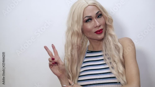 Close-up shot of a beautiful transgender woman making the peace sign with right hand indoors