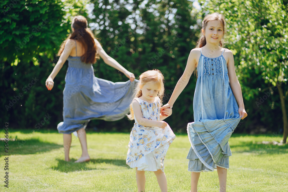 beautiful long-haired mother in a long blue dress in sunny summer forest walks with his beautiful daughters beautiful long-haired mother in a long blue dress in sunny summer forest walks with his beautiful daughters