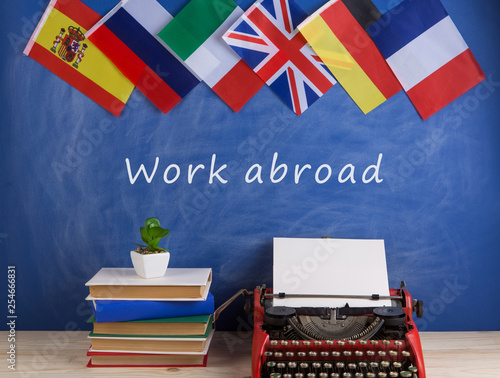 typewriter, flags of Spain, France, Great Britain, books and other countries and blackboard with text "Work abroad"