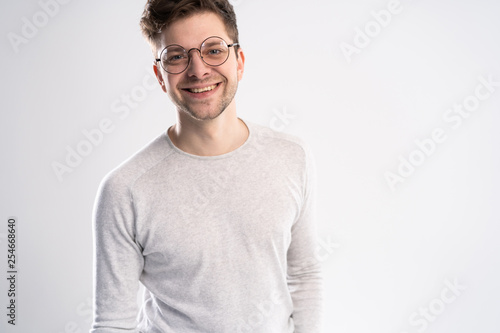 Best smile you ever saw. Portrait of handsome young man looking at camera with smile while standing against white background. © opolja