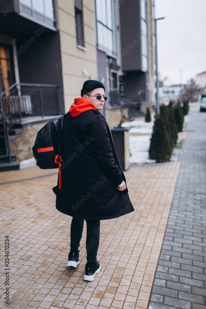 Free handsome independent man walking on street of modern luxury district with backpack in fashionable sun glasses. Freedom,traveller, leader man concept