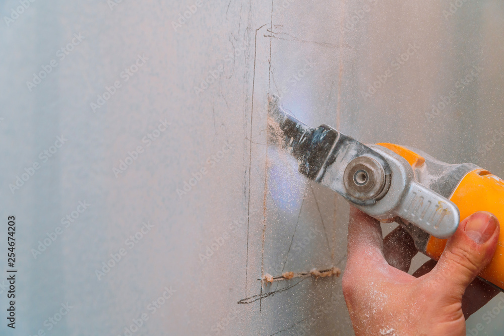Construction worker using a sawsall tool to cut drywall a wall down to