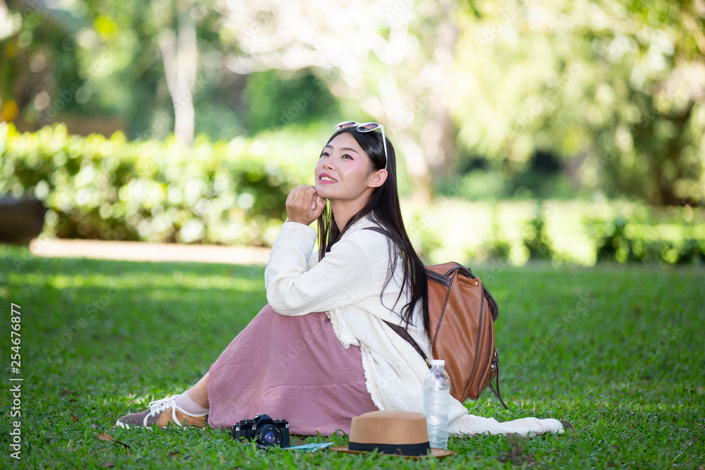 Female tourists who are smiling bright, happy sitting on the grass Female tourists who are smiling bright, happy sitting on the grass