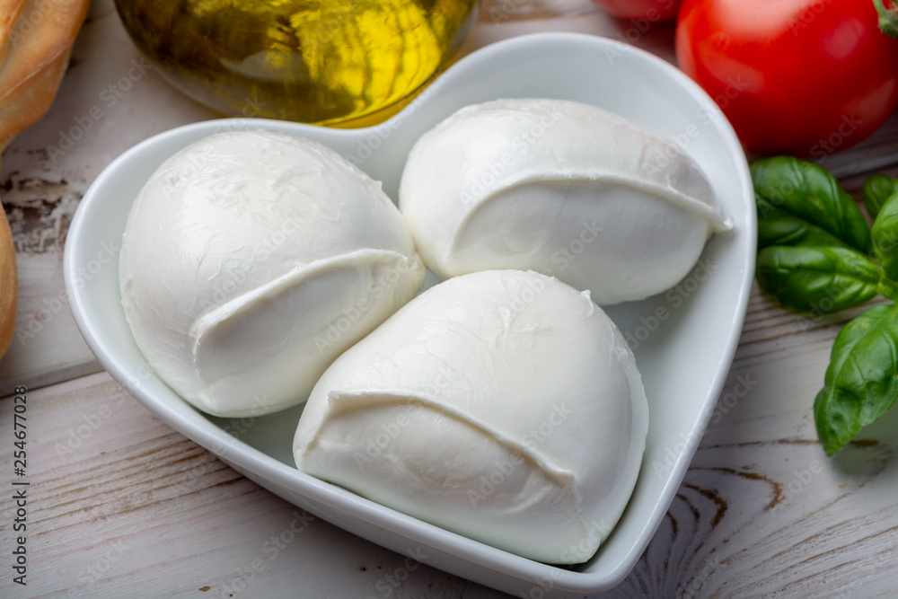 Love mozzerella, balls of buffalo mozzarella, soft Italian scheese made from the milk of Italian Mediterranean buffalo in heart shaped plate