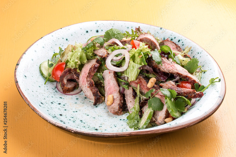 Salad with roast beef and cherry tomatoes on a wooden background