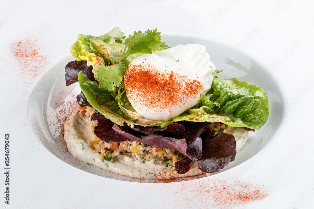 Poached egg with quinoa and salad on a white plate