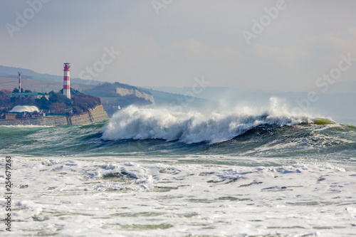 Fototapeta Naklejka Na Ścianę i Meble -  Beautiful and dangerous storm waves on the background of the Gelendzhik lighthouse. Resort Gelendzhik, Caucasus, steep rocky shore.