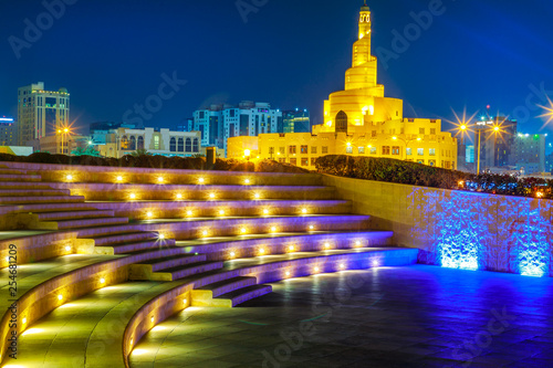 Stairs of small amphitheater at Souq Waqif Garden near Doha Corniche with Doha mosque at night. Doha city center in Qatar, Middle East, Arabian Peninsula in Persian Gulf.