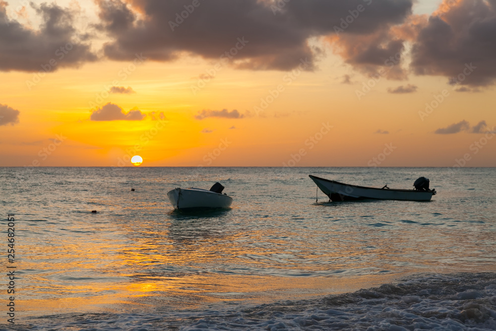 Worthing beach in Barbados at sunset. Two boats in the foreground. Carribean sea