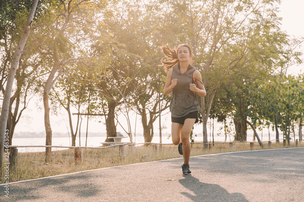 Fototapeta premium young woman runner running on running road in city park