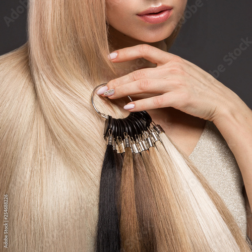 Beautiful blond girl with a perfectly smooth hair, classic make-up with a palette for hair extensions in the hands. Beauty face. photo