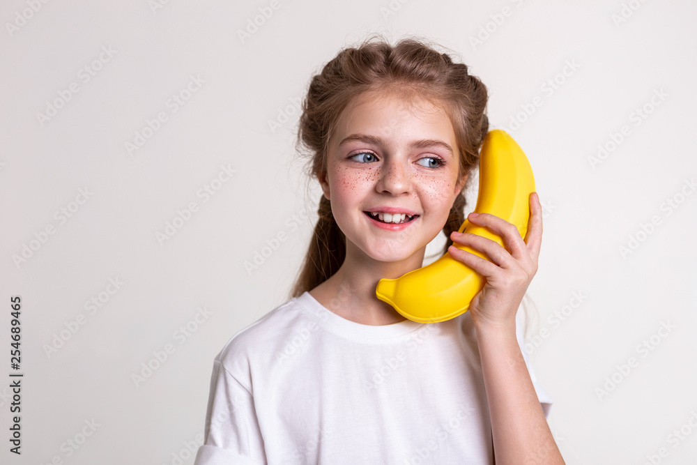 Joyful long-haired child with blue eyes carrying plastic banana Joyful long-haired child with blue eyes carrying plastic banana